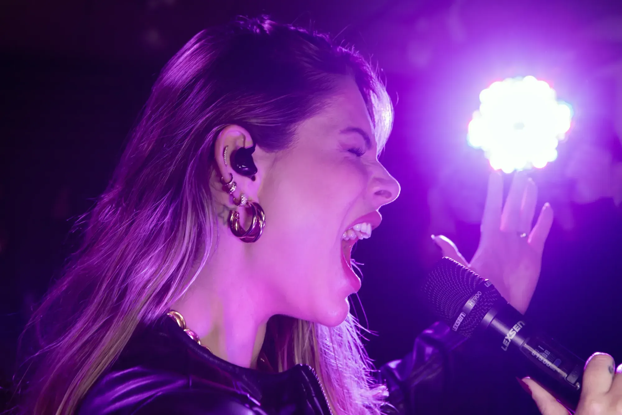 Cantora com monitor in-ear Lexsen cantando sob a luz do palco